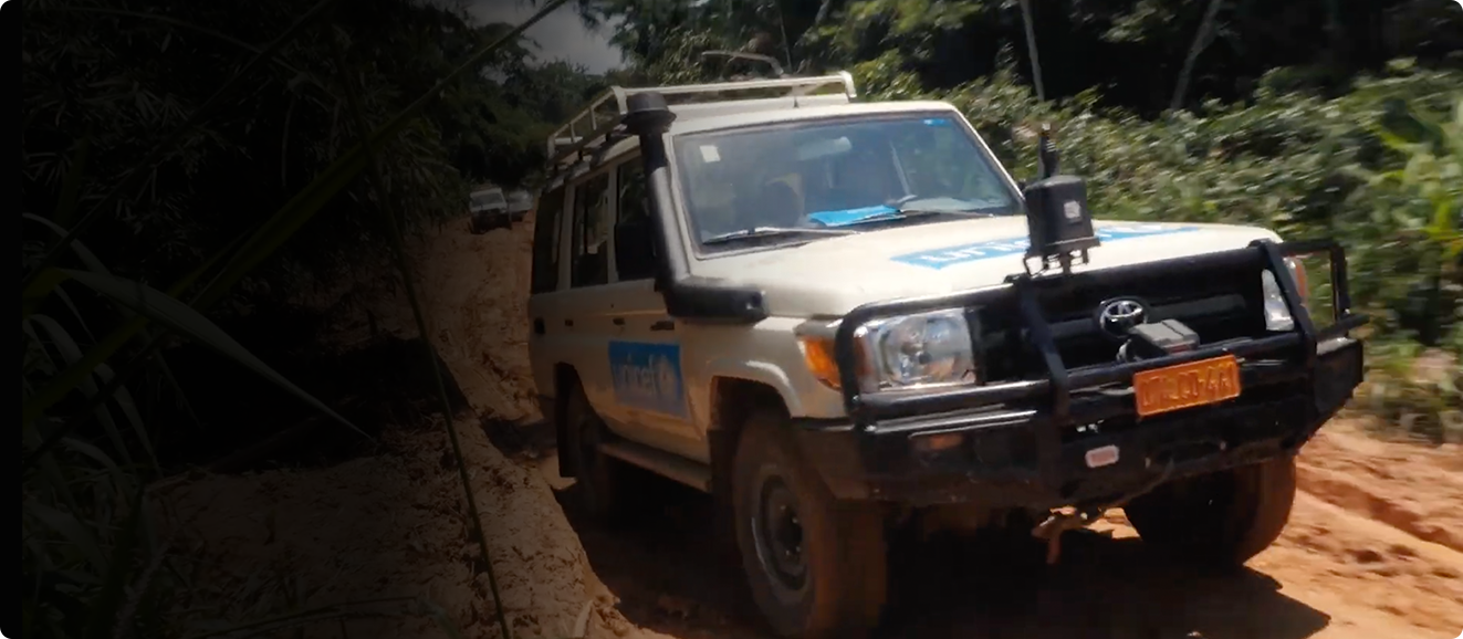 A UNICEF truck drives through a rough dirt road