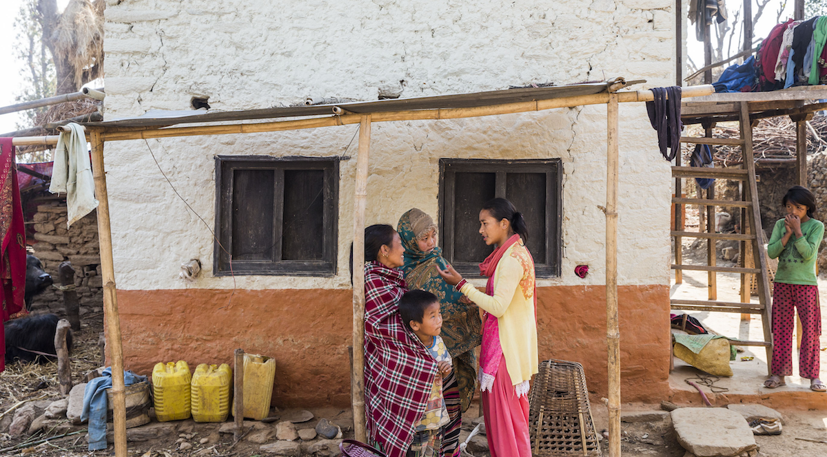  Geeta Thapa Magar, 17, (in brown woollen hat and green shawl) speaks to social worker Kabita Shrestha (in yellow and pink) while Geeta’s maternal aunt Ganga watches them with a young child outside Geeta’s damaged house in Puranagaun village in Ramechhap.