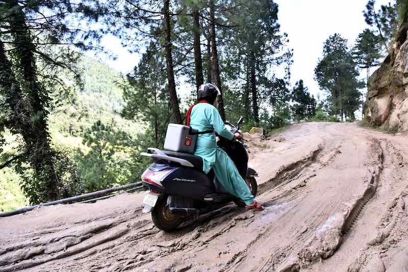 Health worker in India uses motor scooter to reach children with measles vaccine.