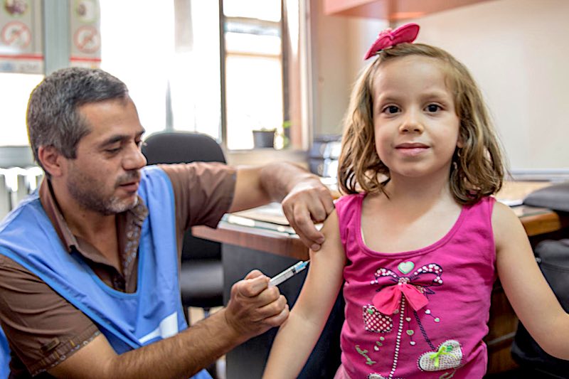 girl gets vaccinated in war-torn Damascus, Syria.
