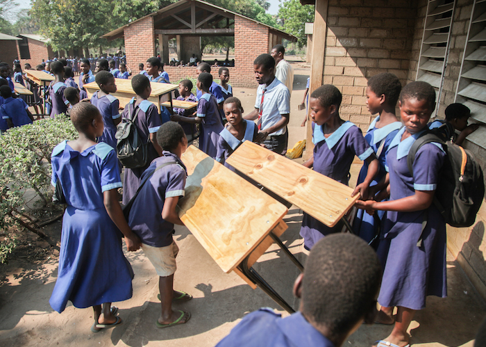 Students help unload new desks at Sotodwa Primary School in Chikwawa, southern Malawi, on Oct. 27, 2022.