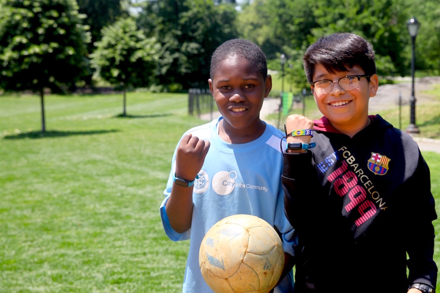 Ibrahim and David show off their UNICEF Kid Power Bands during Lexington Academy&#039;s Field Day in Central Park&#039;s East Meadow.