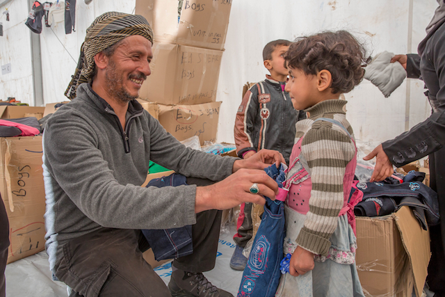 Mohammed buys winter clothes provided by UNICEF for his daughter, Sidra, 4, in Hasahsham camp, Iraq.