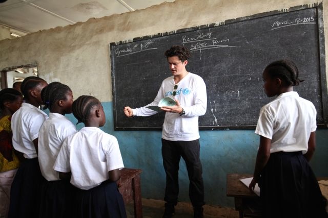 UNICEF Goodwill Ambassador Orlando Bloom reads to students at the Jene Wonde Central Public School in Liberia, which closed in June 2014 due to the Ebola epidemic. After UNICEF launched hygiene training for teachers and students and a community-based Ebol