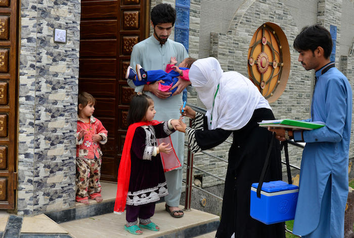 UNICEF-supported health workers and volunteers go door-to-door to vaccinate children against polio in the urban Peshawar, Pakistan. 