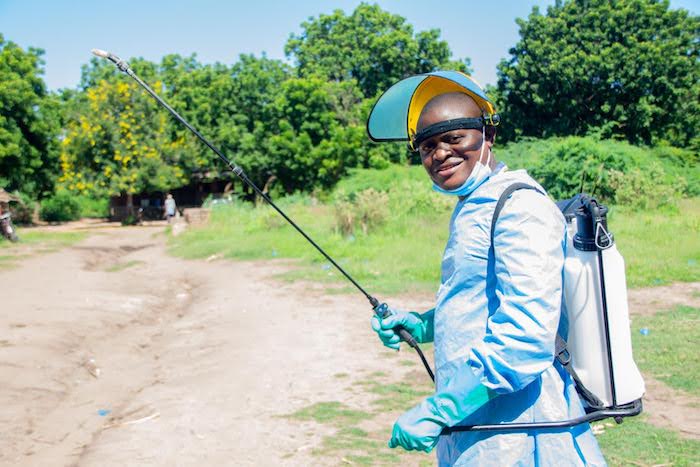 A UNICEF-supported health surveillance assistant suits up to disinfect boats crossing into Malawi from Mozambique to prevent the spread of cholera.