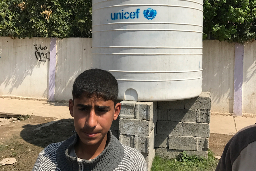 A boy next to a UNICEF-supplied emergency water tank in eastern Mosul, Aleppo.