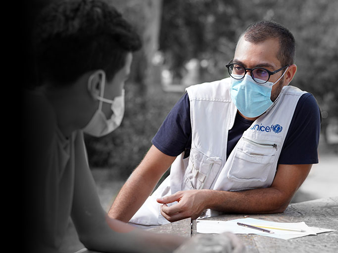 a UNICEF worker gives a health interview to a patient, both people wearing face masks