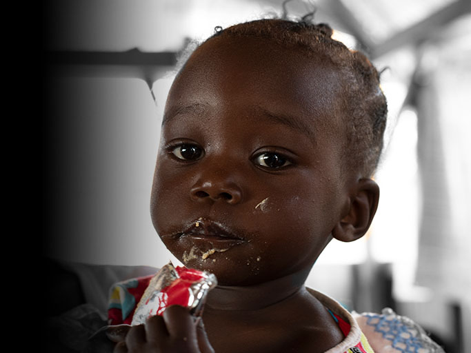 a toddler receives food in a squeezable packet