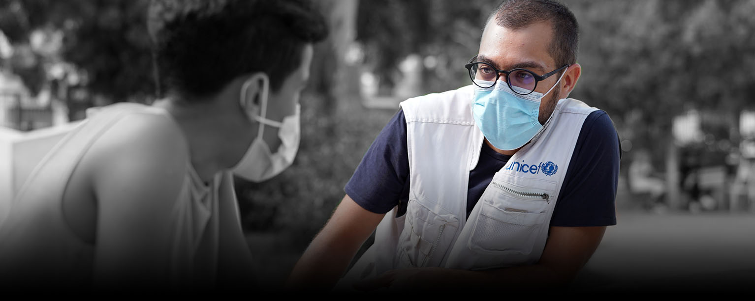 a UNICEF worker gives a health interview to a patient, both people wearing face masks