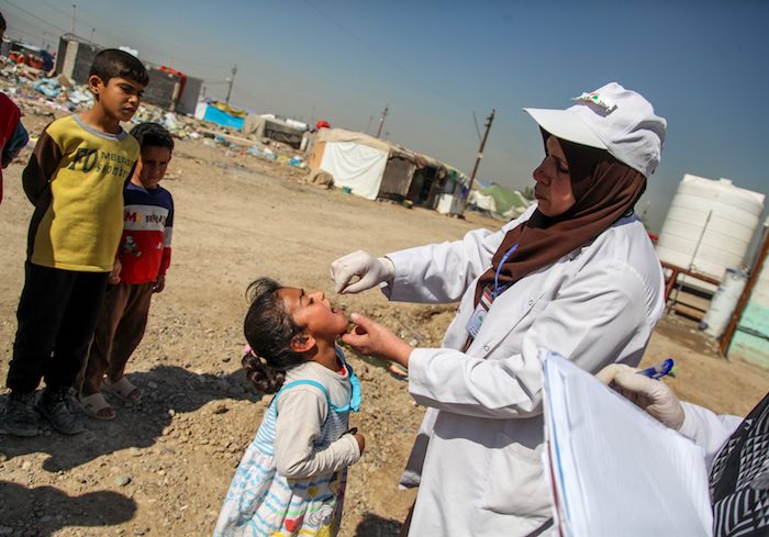 A health worker administers a dose of oral polio vaccine to a child in Baghdad&#039;s Al-Takya Al-Kasnazaniya Camp.