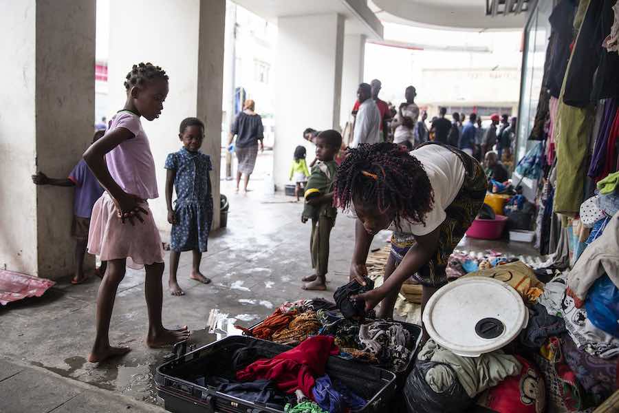 A young girl watches on as a women is busy packing clothes into a suitcase on 20 March 2019. They are living on the street after they were displaced from the informal settlement they were lived in Beira, Mozambique.