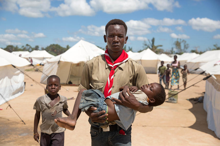 On April 5, 2019 in Dondo, Mozambique, Lucio Carlos, a volunteer social mobilizer, carried Luisa Daniel, 5, suffering from fever and vomiting, to a UNICEF-supported medical tent where she was tested for malaria. 
