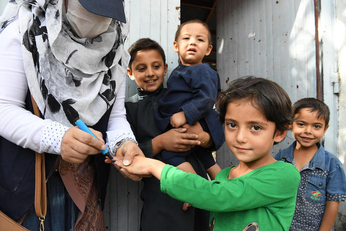 A polio vaccinator going door-to-door in Kart-e-Naw, a suburb of Kabul, Afghanistan, inks a child's finger to show the child has been immunized.