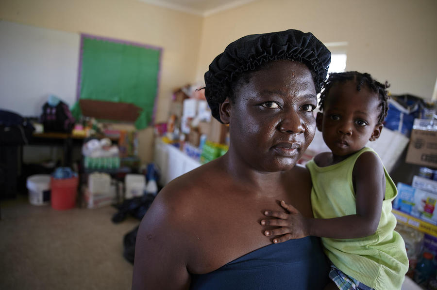 On September 8, 2019 in the Bahamas, Maxenat Gerda holds Christ Bernaida, her 16-month-old daughter, inside a classroom at the Central Abaco Primary School, a temporary shelter in Marsh Harbour.