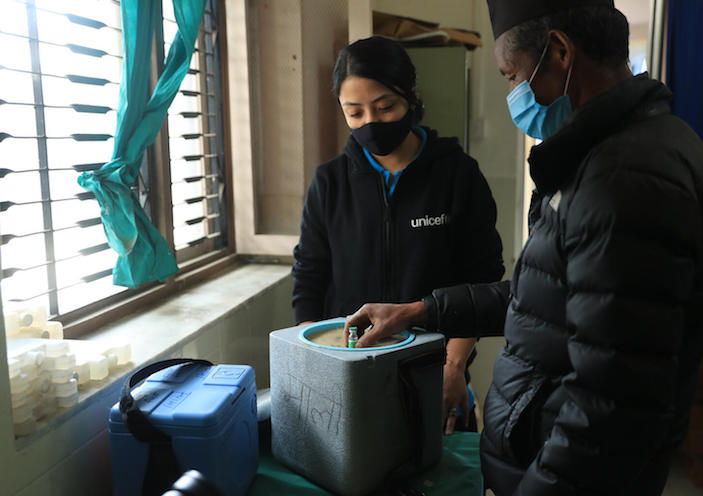 Mitthi Jirel (right), staff at the district hospital in Jiri in Dolakha District in northeastern Nepal, with UNICEF staff Preena Shrestha (left) in the hospital's vaccine store room on 26 February 2021, demonstrating how vaccine boxes are packed.