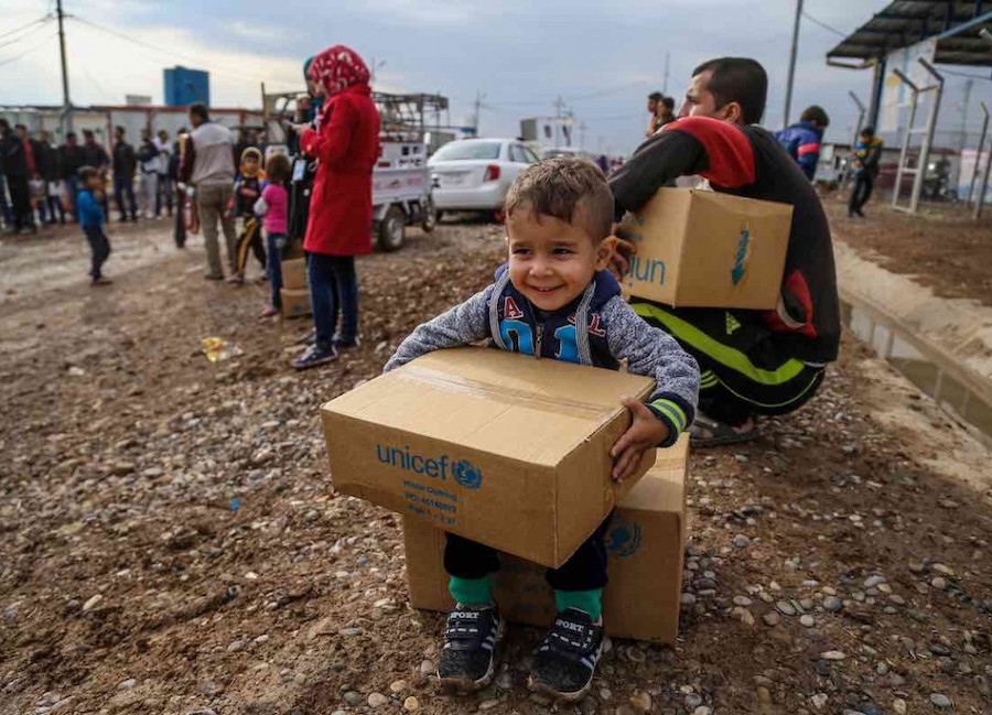 A young Syrian refugee staying at a camp in East Lebanon receives a box of warm winter clothing provided by UNICEF.