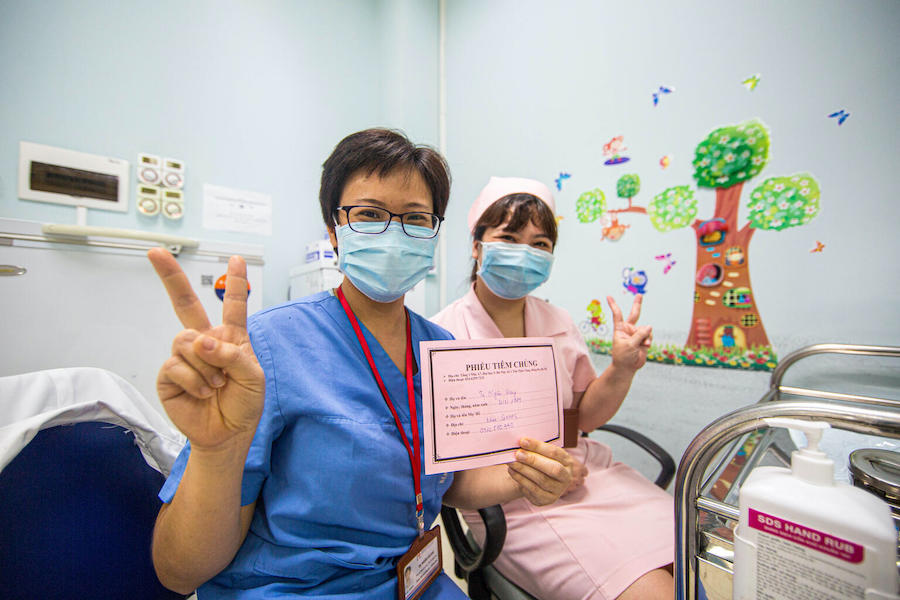 Health workers at Hanoi Medical University in Vietnam flash the "V for vaccinated" sign after receiving their COVID-19 vaccine doses through the COVAX Facility on April 26, 2021. 
