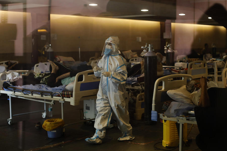 On May 2, 2021, a health worker wearing PPE tends to patients in a banquet hall temporarily converted into a COVID-19 emergency ward in New Delhi, India.