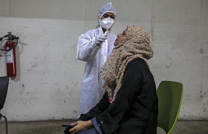 A health worker wearing personal protective equipment takes a nasal swab sample of a person to test for COVID-19 disease at a facility in the Malad area of Mumbai, India.