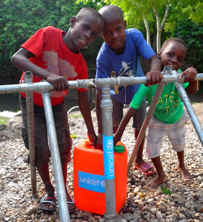 Children in Haiti draw safe water from an access point UNICEF helped install.