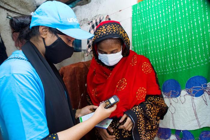 A UNICEF volunteer helps a woman register to get a COVID-19 vaccination in Dhaka, Bangladesh.