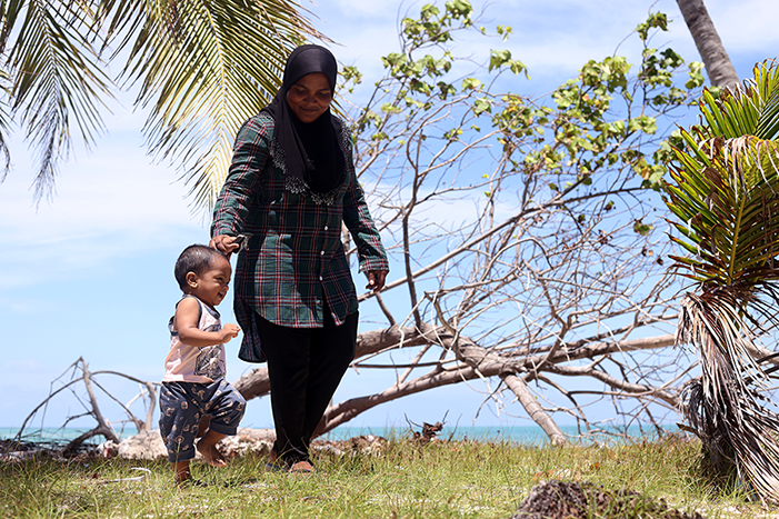 A mother and son on a stretch of severely eroded beach in Dhiffushi island, Maldives.