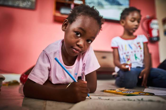 Two girls, ages 5 and 4, draw side by side at a UNICEF-supported safe space for migrant children in Darién Panama.