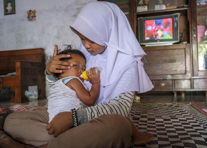 Ayra, 12, comforts her little sister Safia, 2, while caring for her at home in Sragen, Central Java Province, Indonesia.