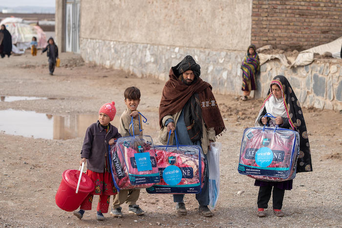 A family in Herat Province, Afghanistan, carries blankets and other supplies provided by UNICEF to protect the most vulnerable from cold winter weather.