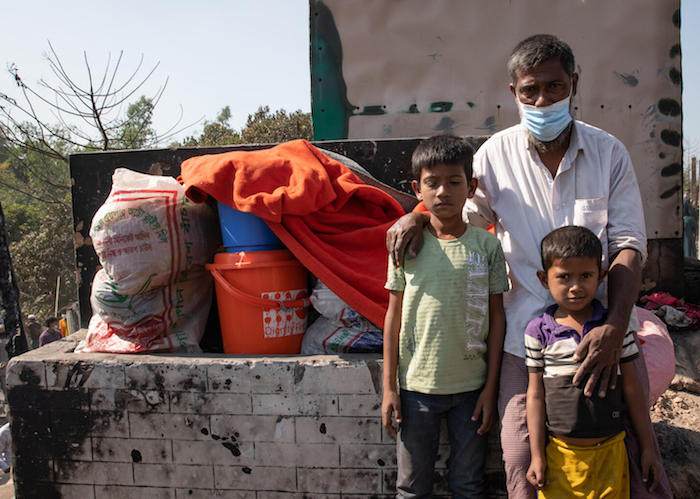 A family stands with their few remaining possessions after a fire destroyed their home in a Rohingya refugee camp in Cox's Bazar, Bangladesh. 