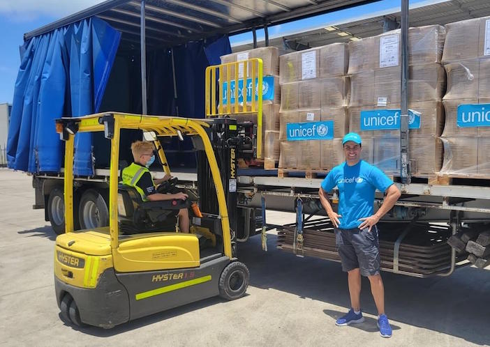 UNICEF Pacific Ambassador Pita Taufatofua stands in front of UNICEF's pre-positioned emergency supplies to be sent to Tonga from Brisbane, Australia.