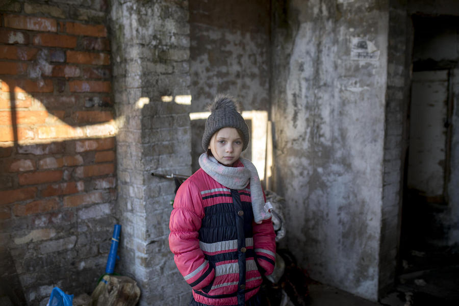 Masha, 9, standing in the entryway to her home, a building in eastern Ukraine that has often been on the front lines of conflict.