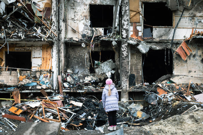 On Feb. 25, 2022, in Kyiv, Ukraine, a girl looks at the crater left by an explosion in front of an apartment building which was heavily damaged during escalating conflict.