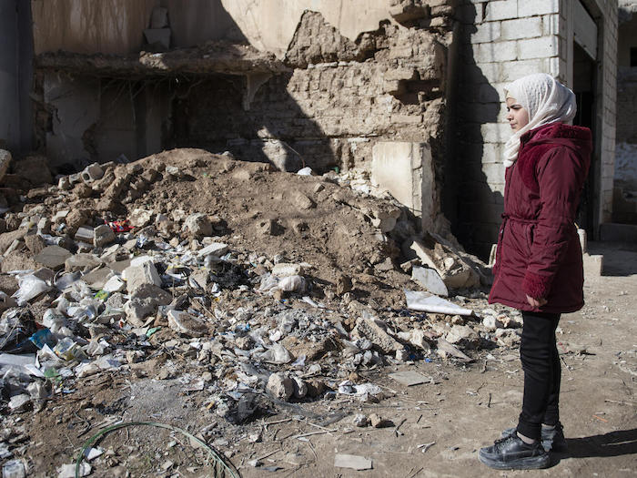 Aminah, 11, of rural Damascus, Syria, looks at the rubble that was once her family's home, destroyed by fighting during the country's civil war.