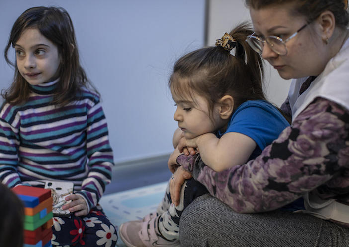 On March 20, 2022 in Chisinau, Moldova, a social worker plays with Sofia, 4, and Arina, 2, in a Child-Friendly Space set up for Ukrainian refugee children at a UNICEF-supported Blue Dot site at the Moldexpo Refugee Accommodation Center.