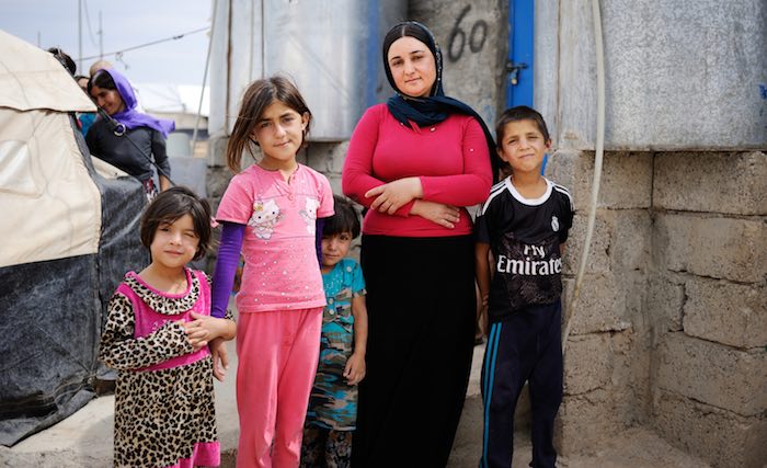 Besma stands with her children outside her tent in Bajet Kandala IDP Camp in Dohuk Governorate. She was shot by a sniper while fleeing her village in Sinjar in August 2014.