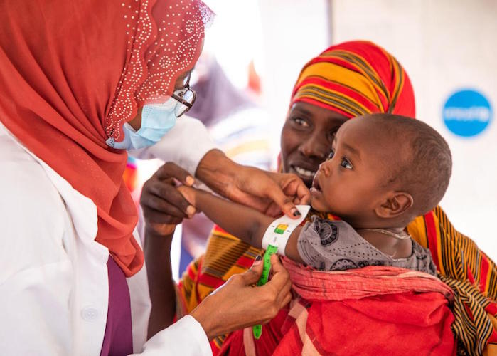 A UNICEF-supported health worker at a site for internally displaced persons in Ethiopia measures the arm of a child to assess his nutrition status. 