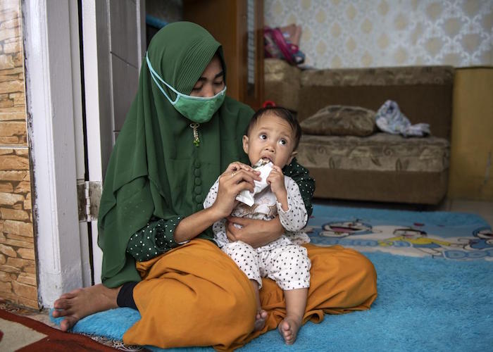 Lisnawati holds her 8-month-old daughter, Adifa, as she eats a packet of nutrient-rich RUTF at home in Bogor, West Java Province, Indonesia.