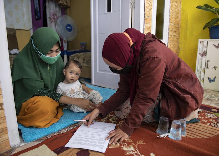 At her home in Bogor, West Java Province, Indonesia, Lisnawati, left, speaks to a field researcher as part of a 2021 Ready-to-Use Therapeutic Food study conducted by UNICEF and partners..