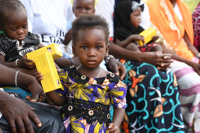 A child in Burkina Faso holds a box of micronutrient powders that UNICEF distributes to help prevent malnutrition in at-risk children.