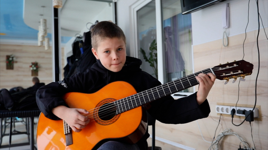 Vitya, 11, playing a guitar that volunteers helped provide after the boy lost all his possessions as his family fled fighting in eastern Ukraine.
