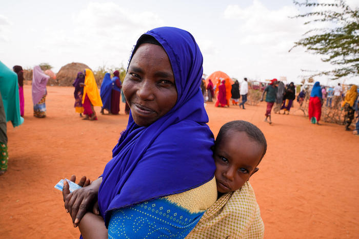 A mother carries her 2-year-old son through the Kaharey camp in Dollow, Somalia, where families displaced by severe drought can access UNICEF support including clean safe drinking water.