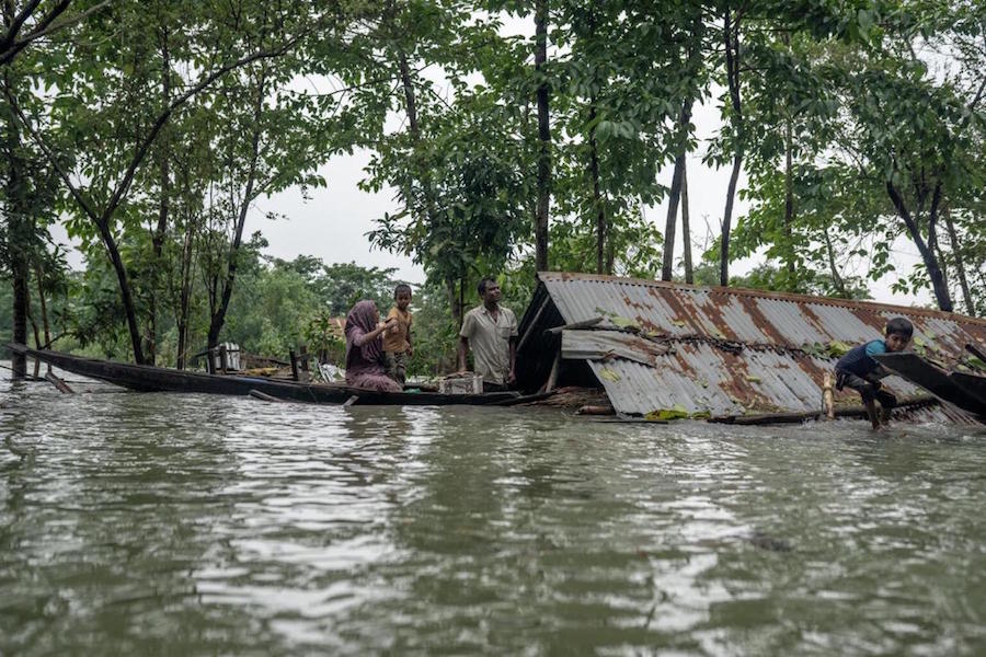 In northeastern Bangladesh, a family leaves their home, submerged by major flooding in June 2022. 