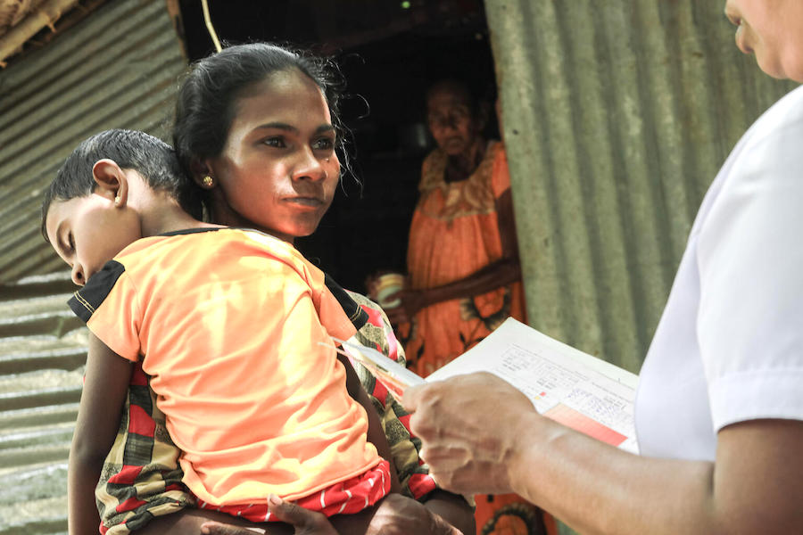 On July 5, 2022 in Devapuram, Batticaloa, Sri Lanka, a mother talks to the local midwife while holding her 3-year-old son, who is underweight. 