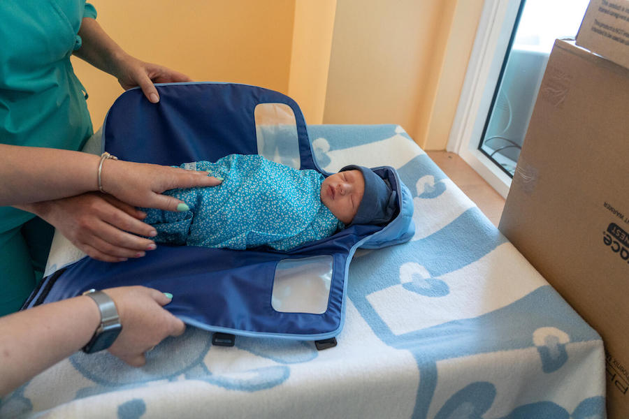 Dr. Valeriya Yankovska, a neonatologist in the Neonatal Intensive Care Unit of the Sumy Regional Perinatal Center in Ukraine, puts a newborn baby girl in a portable infant warmer.