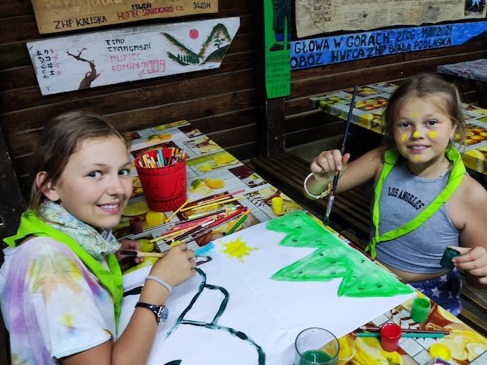 Two 10-year-old girls draw together at a Scouts camp in Poland, August 2022.