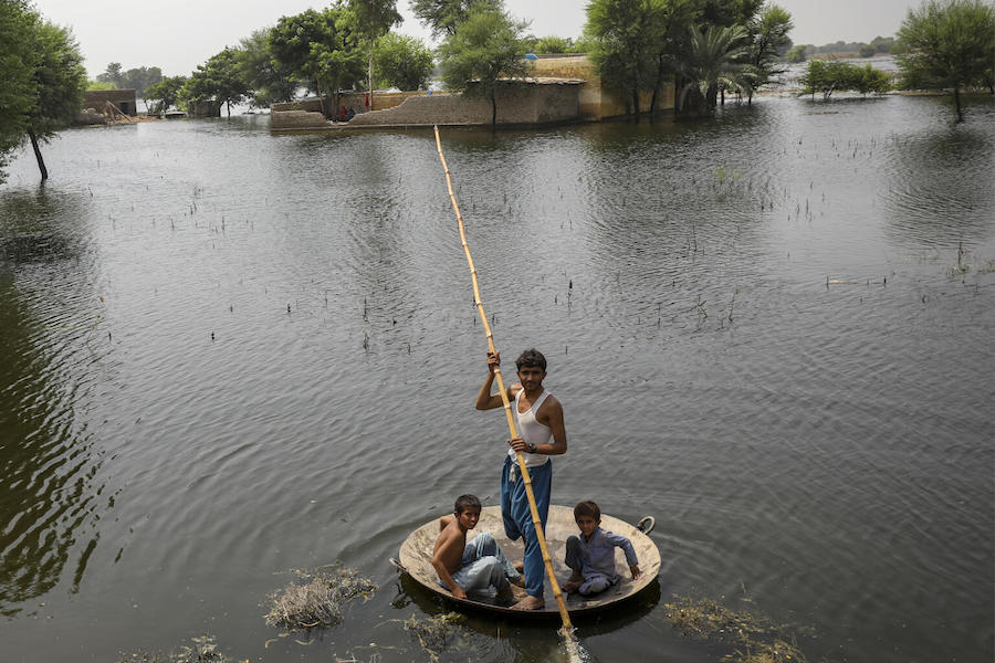Children use a jaggery cooking pan as a boat in flooded Khairpur district, Sindh Province, Pakistan.