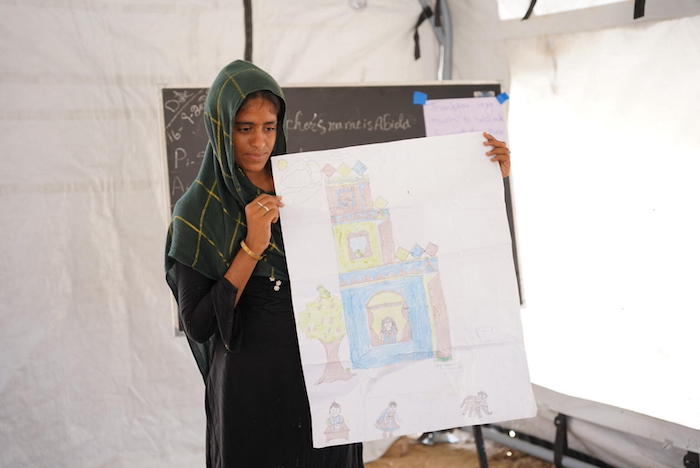 At a UNICEF temporary learning center in near Moenjodaro in Sindh Province’s Larkana District, 17-year-old Kulsoom shows a drawing of the ancestral family home, built by her great-grandfather, that was destroyed by the super floods of 2022.