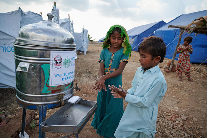 8-year-old Geetu shows her brother how to properly wash hands with soap outside a public toilet at the UNICEF-supported Mohammad Medical Emergency Camp in Umerkot District, Sindh Province, Pakistan.